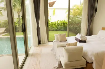 a bedroom with a bed and a chair and windows at Phuket luxury Asherah villa Bang Tao in Ban Phru Champa