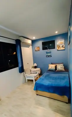 a blue bedroom with a bed and a chair at Leamsai Whisper Home in Thalang
