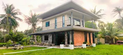 a house with a balcony on a lawn with palm trees at Leamsai Whisper Home in Thalang