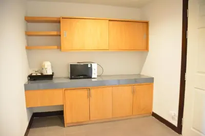 a kitchen with wooden cabinets and a microwave at Zephyr Suites in Patong Beach