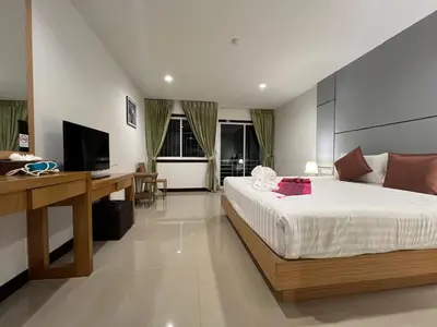 a bedroom with a bed and a desk and a television at Zephyr Suites in Patong Beach
