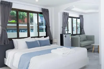 a bedroom with a large white bed and a chair at Brickotel Naithon Beach in Nai Thon Beach