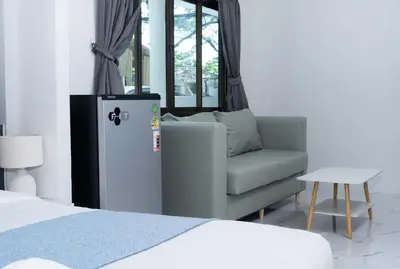 a living room with a chair and a refrigerator at Brickotel Naithon Beach in Nai Thon Beach