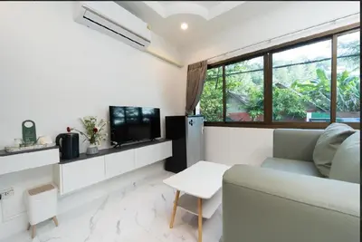 a living room with a couch and a tv at Brickotel Naithon Beach in Nai Thon Beach
