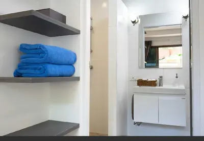 a bathroom with blue towels on a shelf and a sink at Brickotel Naithon Beach in Nai Thon Beach