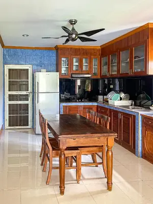 a kitchen with a wooden table and a ceiling fan at The Beige Pool Villa Bang Tao Phuket in Ban Thalat Choeng Thale