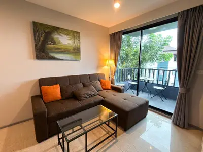 a living room with a couch and a balcony at 6th Avenue 2 bedroom in Surin Beach