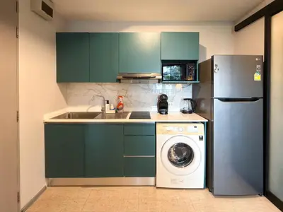 a kitchen with green cabinets and a washing machine at 6th Avenue 2 bedroom in Surin Beach