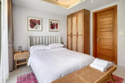 a bedroom with a large white bed and a wooden door at Botanica Luxury Pool Villa Phuket in Thalang