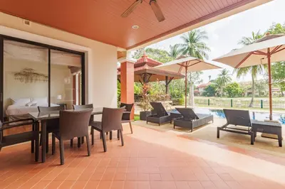 an outdoor patio with a bed and tables and chairs at Spacious Villa with Pool, Garden & Club facilities in Layan Beach