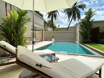 a swimming pool with chairs and an umbrella next to a house at Luxury Pool Villa Bangtao Phuket close to beach in Bang Tao Beach