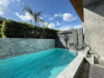 a swimming pool in a backyard with a stone wall at Chalong Modern 2 bedroom pool villa in Ban Suan