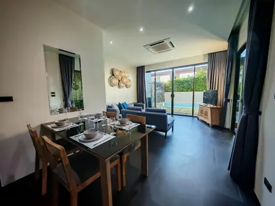 a living room with a table and chairs and a couch at Chalong Modern 2 bedroom pool villa in Ban Suan