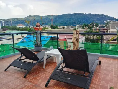 a patio with two chairs and a table on a balcony at Kata Lina rooftop in Kata Beach