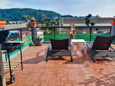 a patio with two chairs and a table on a roof at Kata Lina rooftop in Kata Beach