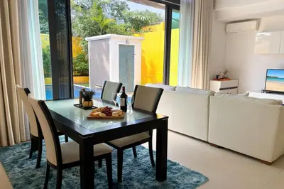 a dining room with a table and chairs and a couch at Tropical 2 BR Pool Villa - Baan Wana 177-15 in Koh Lone