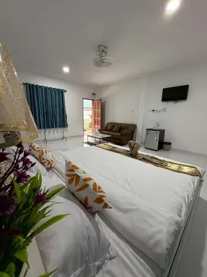 a large white bed in a living room with a couch at AN Airport Guesthouse in Nai Yang Beach