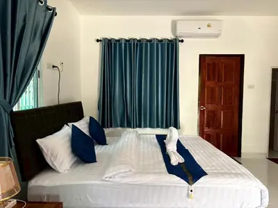 a bedroom with a large bed with blue curtains at AN Airport Guesthouse in Nai Yang Beach