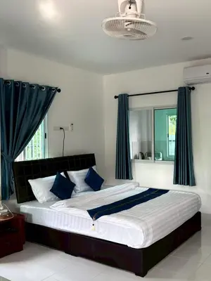 a bedroom with a large bed with blue curtains at AN Airport Guesthouse in Nai Yang Beach