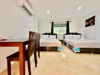 a room with two beds and a table and a desk at Jasmine Residence in Patong Beach