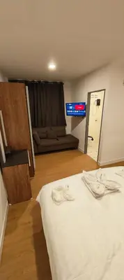 a bedroom with a bed with a couch in the background at Tiger Nanai guest house in Patong Beach