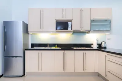 a kitchen with white cabinets and a stainless steel refrigerator at Private villa at Oxygen Bangtao -pool garden BBQ in Ban Thalat Choeng Thale