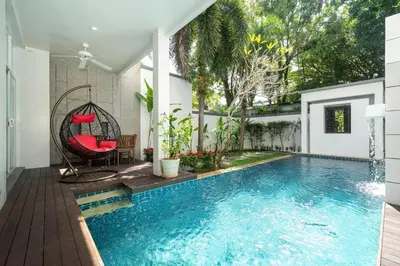 a pool with a swing and a red chair next to a house at Private villa at Oxygen Bangtao -pool garden BBQ in Ban Thalat Choeng Thale