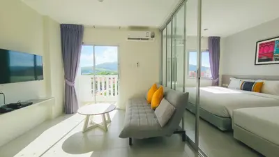 a bedroom with a bed and a couch and a window at Recenta Suite Phuket Suanluang in Phuket Town
