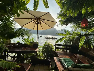 a table with an umbrella in front of a body of water at Nanworld travel sea view room in Phi Phi Don