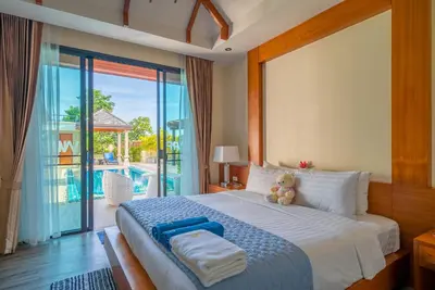 a teddy bear sitting on a bed in a bedroom at Rawayana West Villas & Kids Park in Rawai Beach