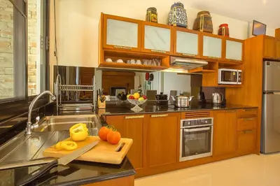 a kitchen with wooden cabinets and a cutting board at Rawayana West Villas & Kids Park in Rawai Beach