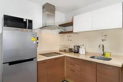 a kitchen with a stainless steel refrigerator and wooden cabinets at Karon Sea View 2 Bedrooms Apartment in Karon Beach