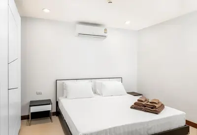 a white bedroom with a bed with towels on it at Karon Sea View 2 Bedrooms Apartment in Karon Beach