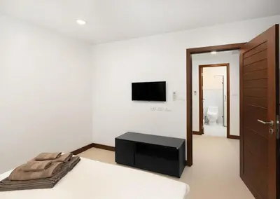 a bedroom with a bed and a tv on the wall at Karon Sea View 2 Bedrooms Apartment in Karon Beach
