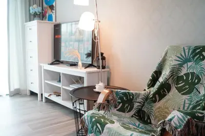 a living room with a chair and a tv at Title - Comfortable 1BR Tropical Retreat in Nai Yang Beach