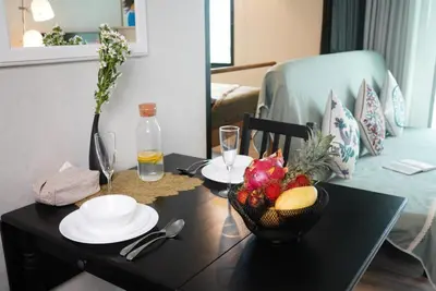 a table with a bowl of fruit and a bottle of wine at Title - Comfortable 1BR Tropical Retreat in Nai Yang Beach
