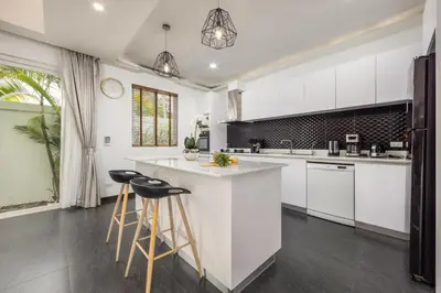 a kitchen with white cabinets and bar stools at Villa Hemi 2BR Modern Thai Style with Private Pool in Rawai Beach