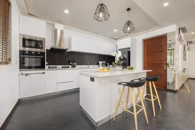 a kitchen with white cabinets and a island with bar stools at Villa Hemi 2BR Modern Thai Style with Private Pool in Rawai Beach