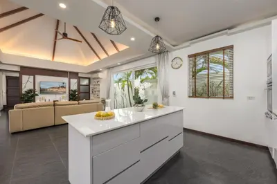 a kitchen with white cabinets and a living room at Villa Hemi 2BR Modern Thai Style with Private Pool in Rawai Beach