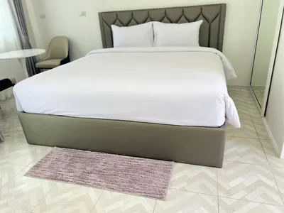 a bed with white sheets and a rug in a room at Sarona House 3 in Ban Thalat Choeng Thale
