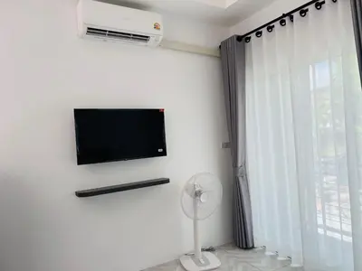 a room with a tv and a fan and a window at Sarona House 3 in Ban Thalat Choeng Thale