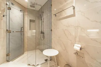 a bathroom with a shower and a toilet and a stool at Cassia Residence by Villacarte in Laguna Phuket