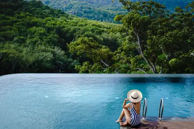 a woman sitting on the edge of a pool of water at Duplex 1 BR Apt UTL B112 - Direct Pool Access in Rawai Beach