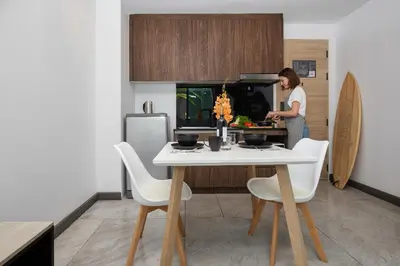 a woman standing in a kitchen with a table at Duplex 1 BR Apt UTL B112 - Direct Pool Access in Rawai Beach