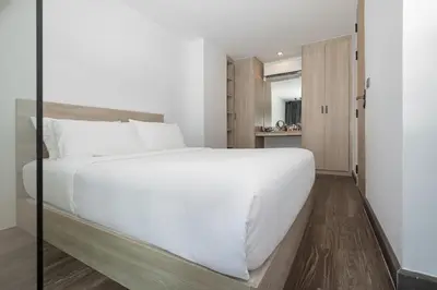 a bedroom with a large white bed and a mirror at Duplex 1 BR Apt UTL B112 - Direct Pool Access in Rawai Beach