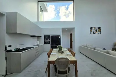 a kitchen and living room with a table and a couch at 3BR Pool Villa JAAI in Ban Saiyuan (1)