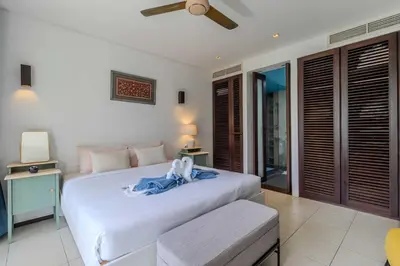 a bedroom with a white bed with a blue robe on it at C254 Condo 2BR Pool View Short Walk to Beach in Thalang