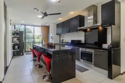 a kitchen with black counter tops and red stools at C254 Condo 2BR Pool View Short Walk to Beach in Thalang
