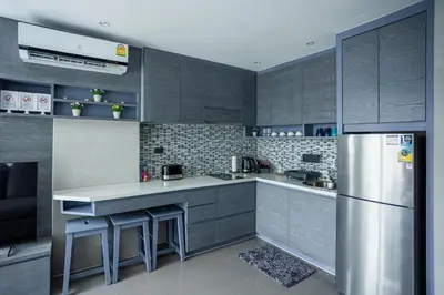 a kitchen with gray cabinets and a stainless steel refrigerator at C252 Great Facility Condo Near Beach & Rooftop Pool in Kamala Beach