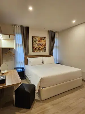 a bedroom with a large white bed and a table at Wora Phuket in Ban Sam Kong